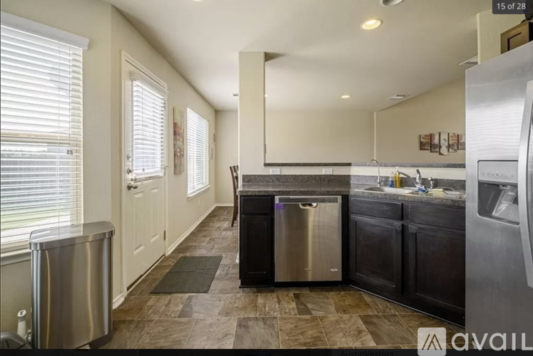 A kitchen with a stainless steel refrigerator and a trash can.