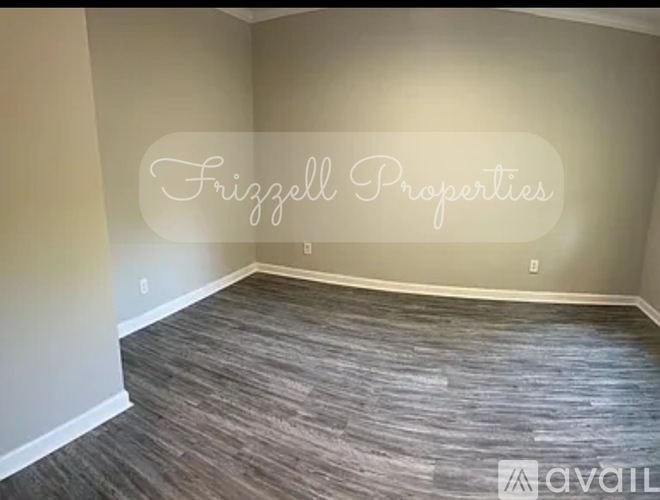 A room with wooden flooring and a wall with a switch and outlet.