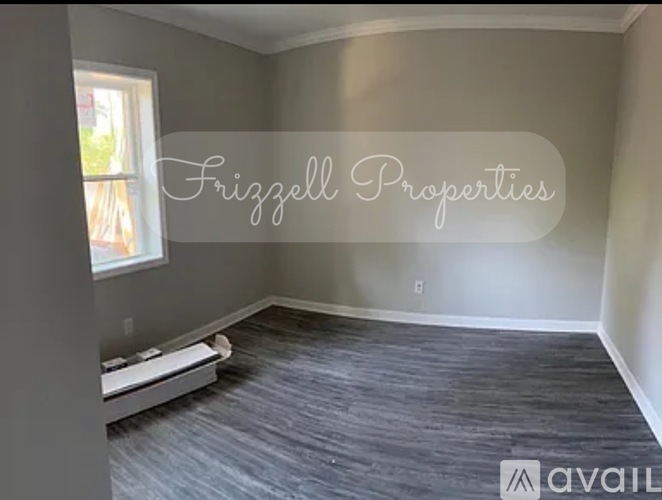 A room with a window and a radiator, with the text "Frigzell Properties" and "available" on the wall.