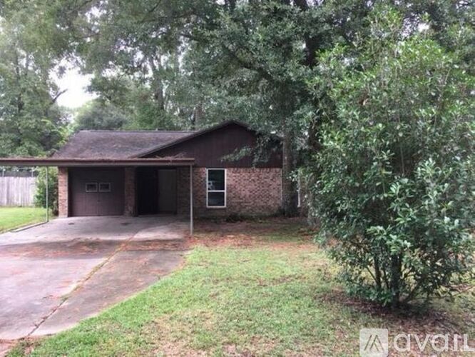 A house with a garage and a driveway is surrounded by trees.