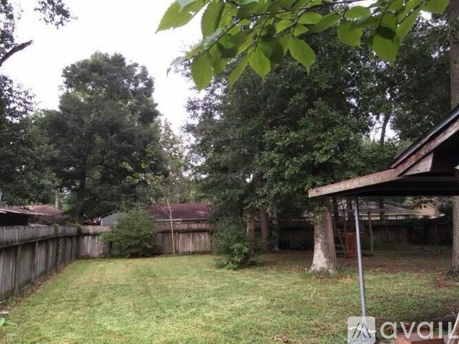 A backyard with a wooden fence and a tree.