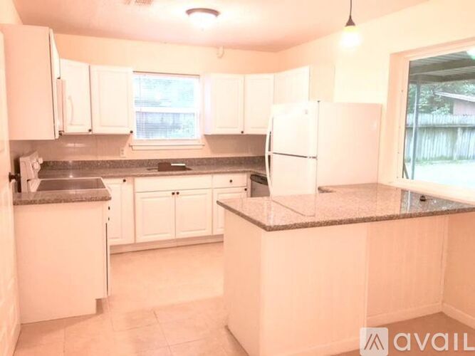 A kitchen with white cabinets and a granite countertop.