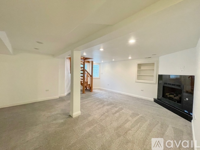 A spacious living room with a fireplace and a staircase.