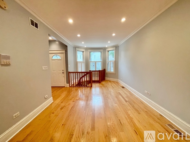 A spacious room with wooden floors and a staircase leading to another level.