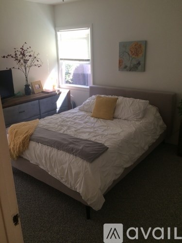 A bedroom with a bed, nightstand, and window.