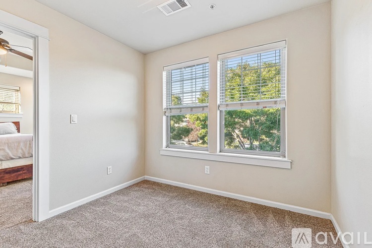 A room with a window showing a view of trees and bushes.