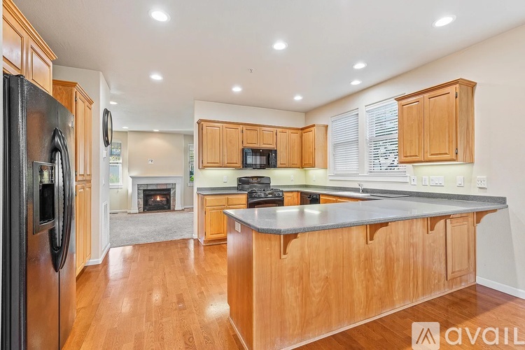 A kitchen with wooden cabinets and a black refrigerator.