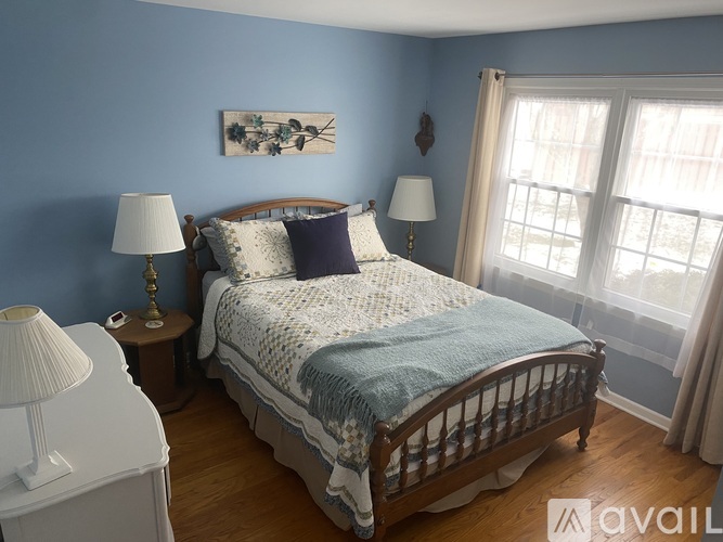 A bedroom with a bed, two lamps, and a painting on the wall.