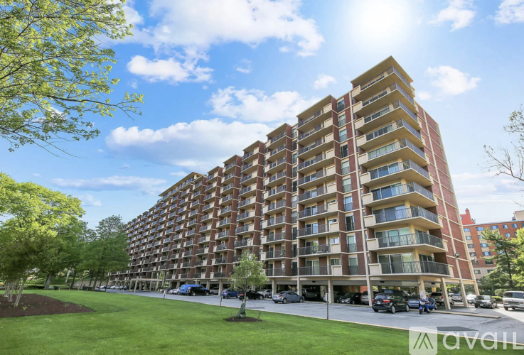 A tall apartment building with a parking lot in front.
