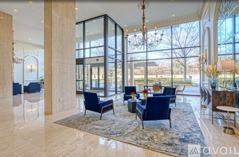 A spacious living room with a large rug and blue chairs.