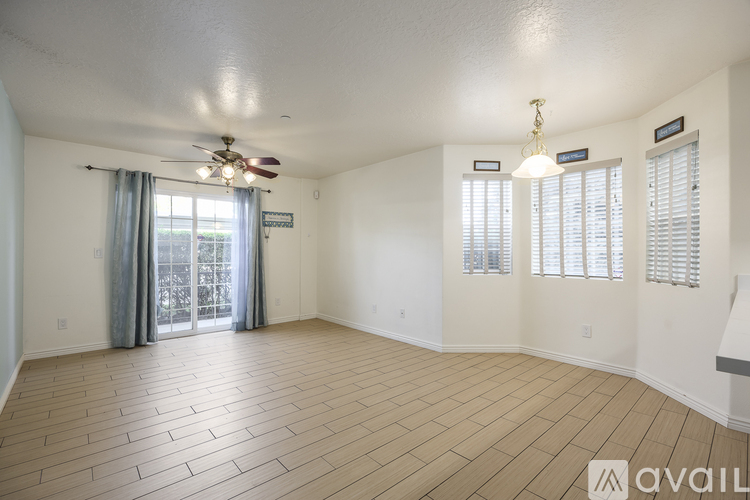 A spacious room with a ceiling fan and wooden flooring.
