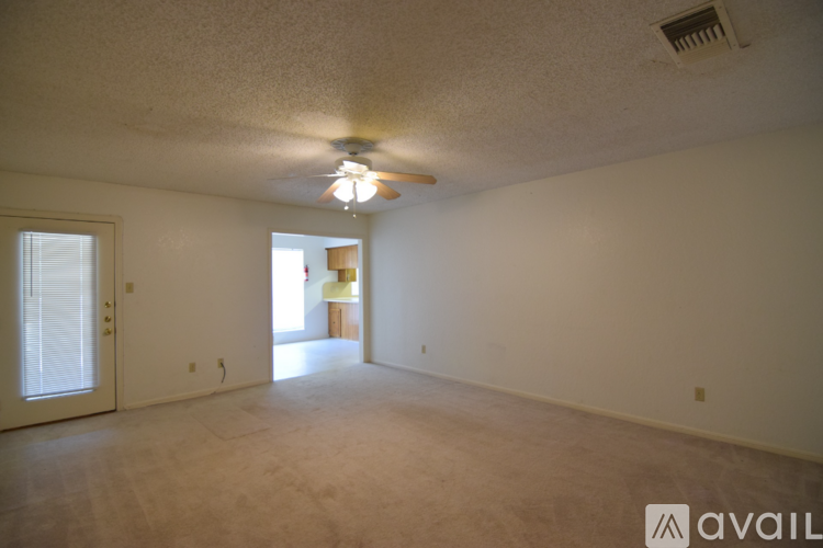 A room with a ceiling fan and a door leading to another room.