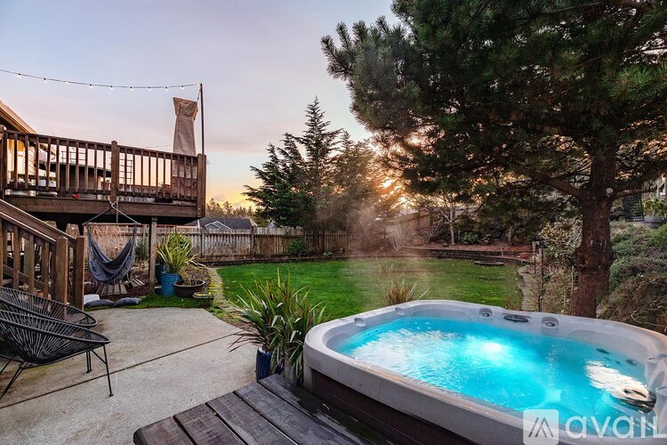 A hot tub is surrounded by a deck and a backyard.