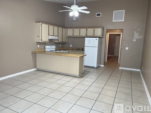 A kitchen with a white fridge and a fan on the ceiling.