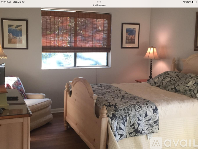 A bedroom with a bed, nightstand, and window with blinds.