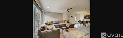 A modern living room with a grey sofa and a glass table.