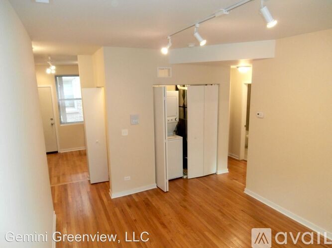 A room with wooden floors and white walls, with a door open to a hallway.