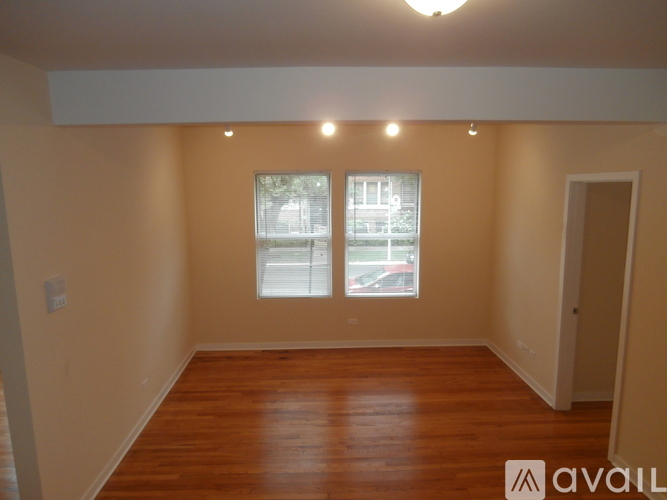 A room with wooden floors and a window showing a street view.