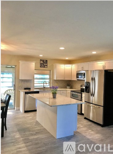 A kitchen with a large island in the middle and a refrigerator to the right.