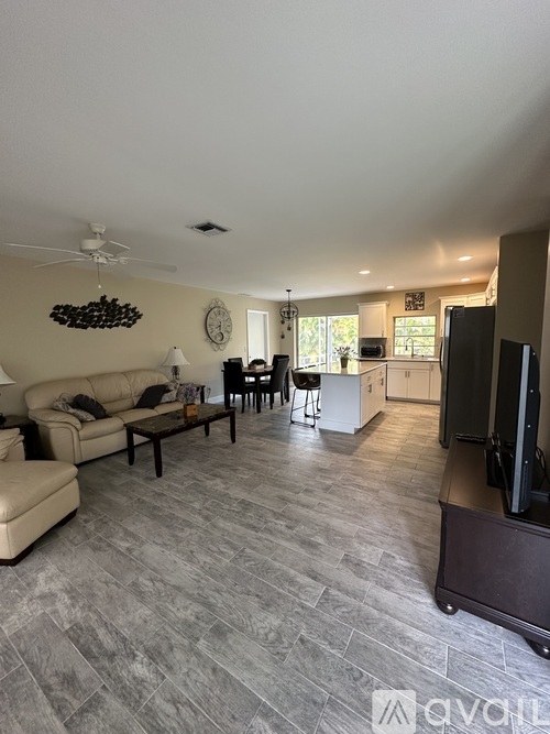 A living room with a couch, chairs, and a television.