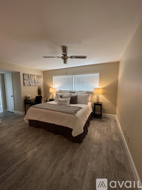 A bedroom with a bed, two lamps, and a ceiling fan.