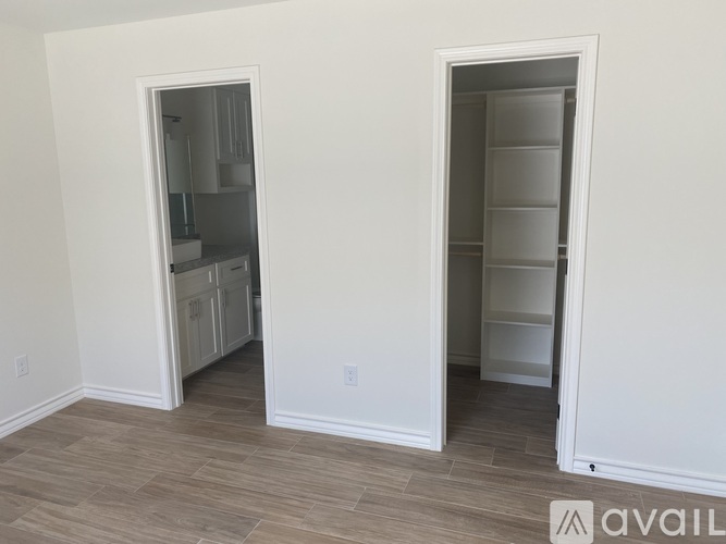 Two white doors open to reveal empty rooms with white walls.