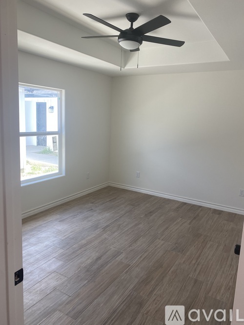 A room with a ceiling fan and light, and a window letting in light.