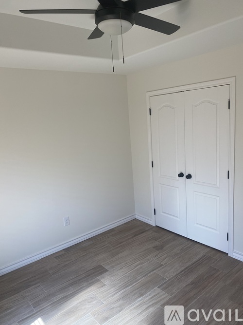 A room with a white door and a ceiling fan.