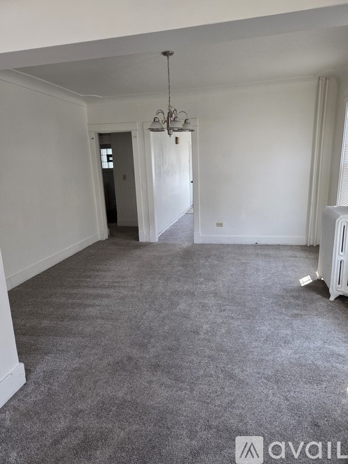 A room with grey carpet and a chandelier.