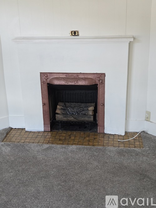 A fireplace with a white mantle and a fire place with a brick border.