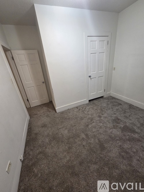 A room with a carpeted floor and two doors.