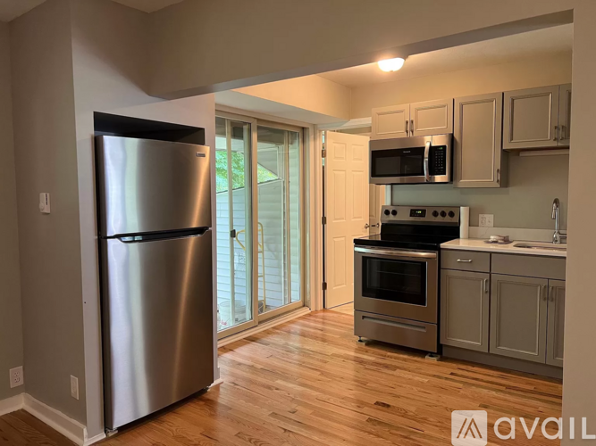 A kitchen with a stainless steel refrigerator and wooden floors.