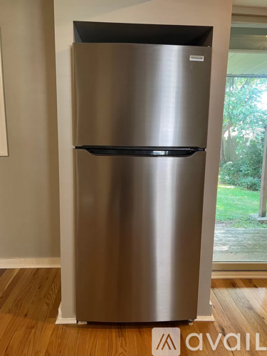 A stainless steel fridge with a black door and a white label on the top.