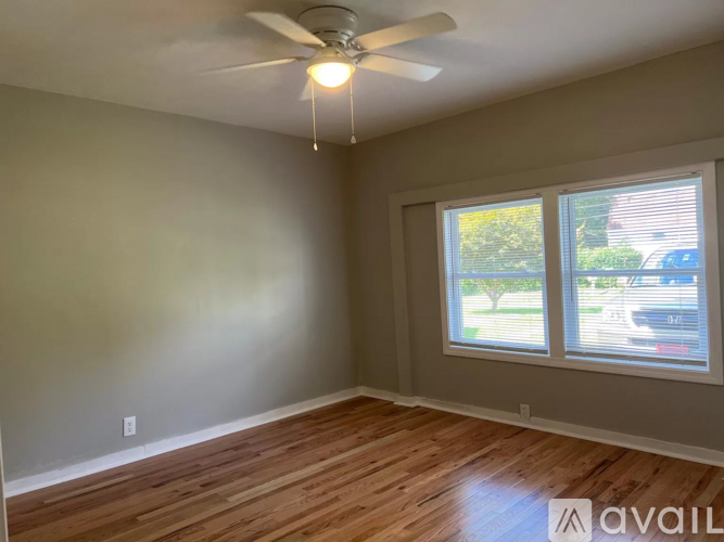 A room with a ceiling fan and wooden flooring.