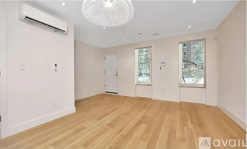A room with wooden flooring and a chandelier hanging from the ceiling.