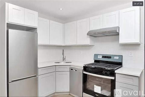 A kitchen with white cabinets and a stainless steel refrigerator.