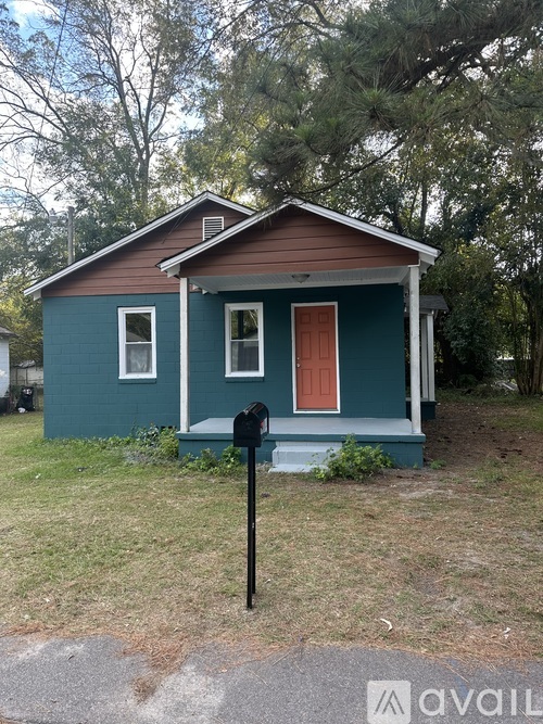 A small blue house with a red door and a mailbox in front.