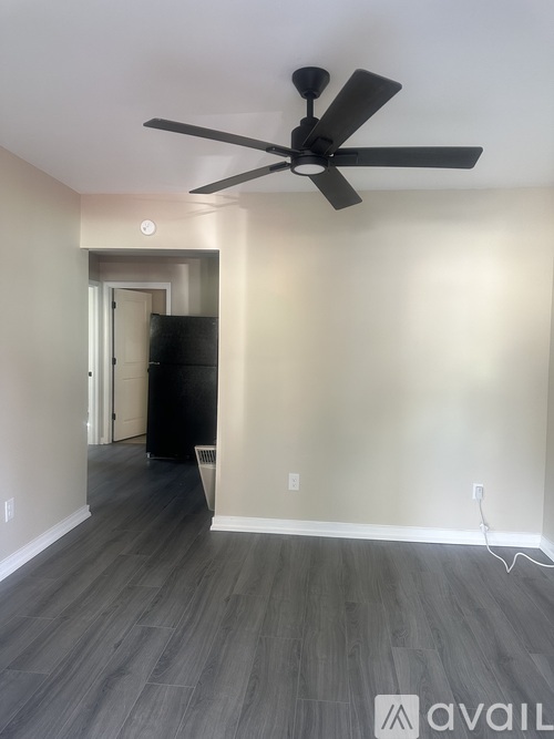 A room with a ceiling fan and wooden flooring.