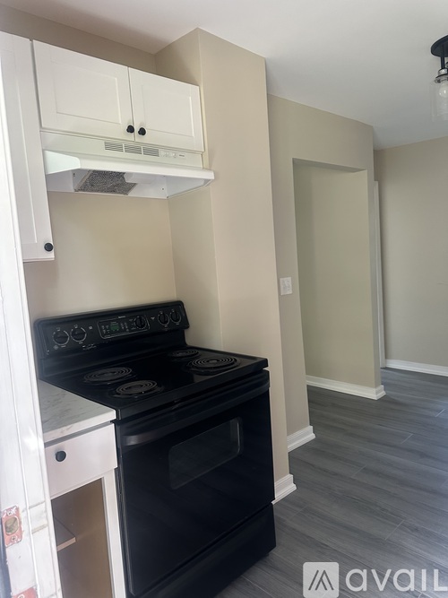 A black stove is in a kitchen with white cabinets.