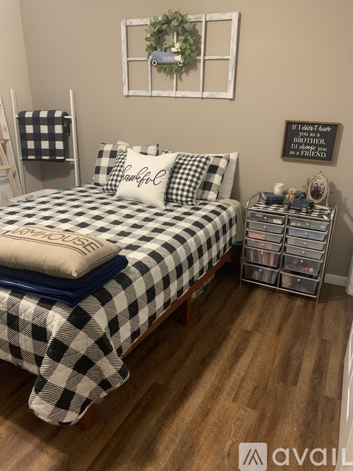 A bedroom with a bed, nightstand, and a wall hanging with a quote.