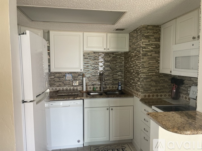 A kitchen with white appliances and a stone backsplash.