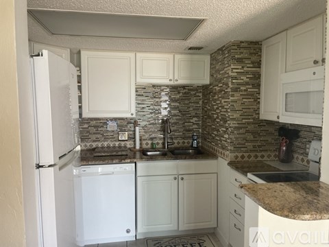 A kitchen with white appliances and a stone backsplash.