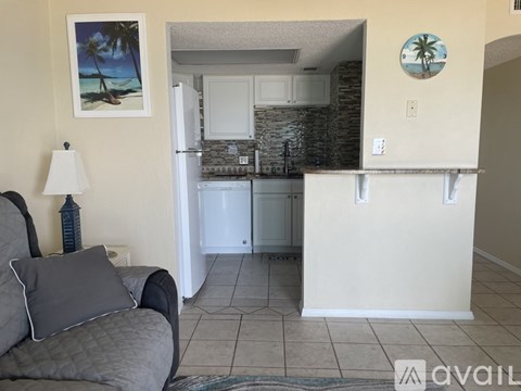 A living room with a grey couch and a painting of a beach scene on the wall.