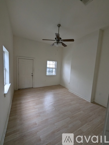 A room with a ceiling fan and wooden flooring.