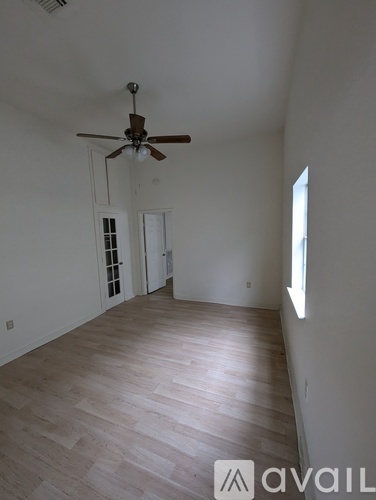 A room with a ceiling fan and wooden flooring.