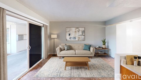 A living room with a couch, a rug, a coffee table, and a painting on the wall.