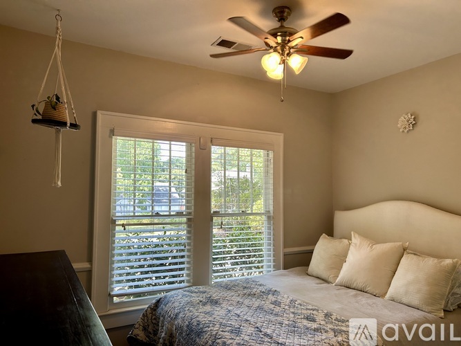 A bedroom with a bed, a ceiling fan, and a window with blinds.