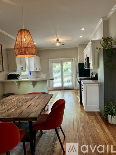 A kitchen with a wooden table and red chairs.