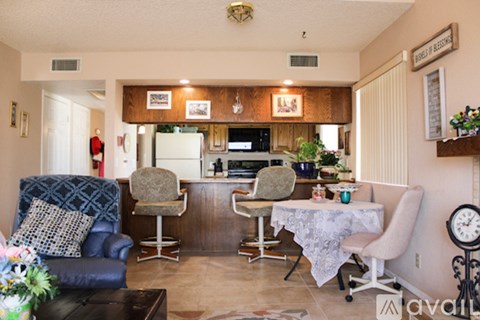 A living room with a blue chair and a dining table with chairs.