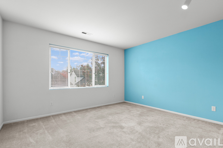A room with a window showing a view of trees and a blue wall.